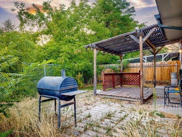 Yard at dusk with a fenced backyard, a deck, a patio area, and a pergola