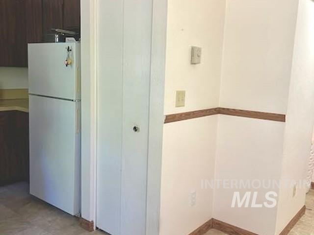 Kitchen with freestanding refrigerator and dark brown cabinetry