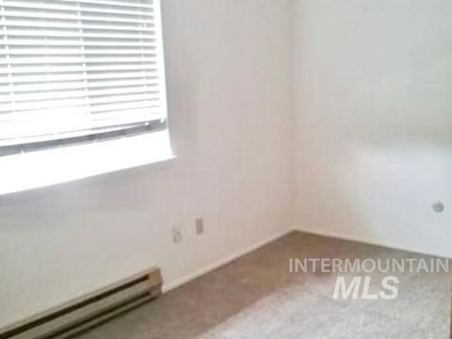 Spare room featuring a baseboard radiator and carpet flooring