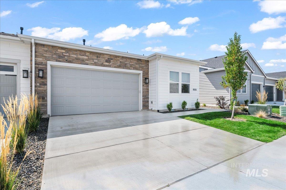 Single story home with stone siding, concrete driveway, and an attached garage