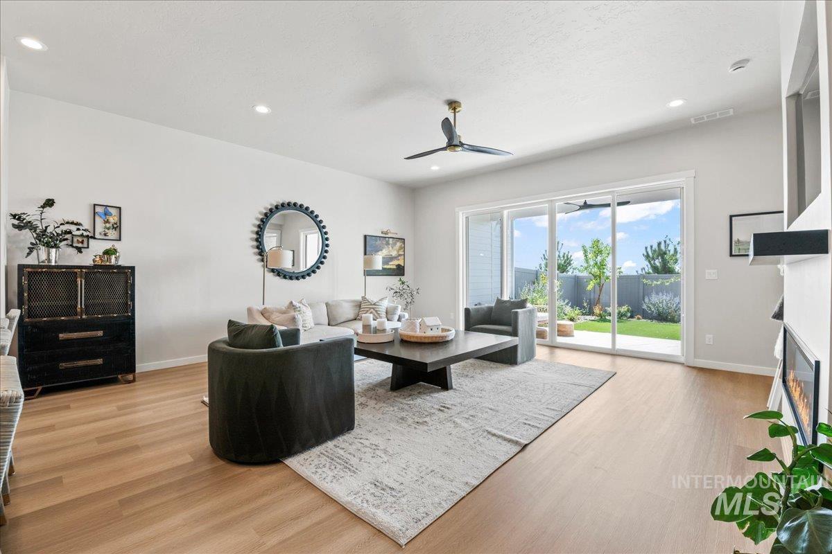 Living area with a ceiling fan, light wood-style floors, recessed lighting, and a fireplace with flush hearth