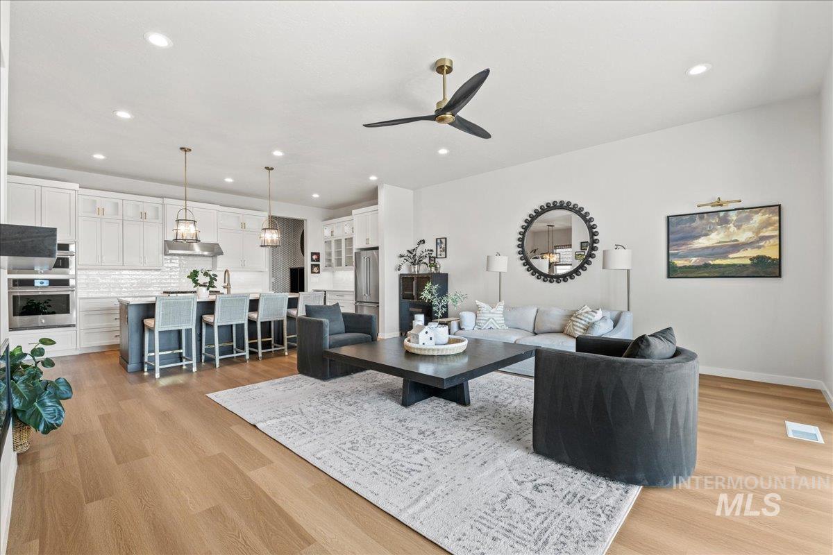 Living area with a ceiling fan, recessed lighting, and light wood finished floors