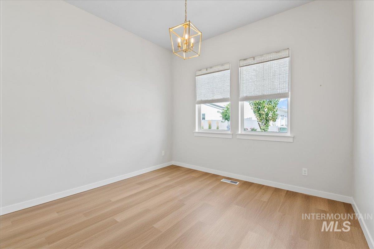 Spare room featuring light wood-type flooring and a chandelier