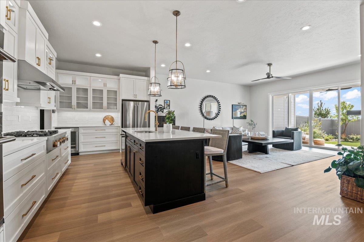 Kitchen featuring a breakfast bar area, hanging light fixtures, white cabinets, recessed lighting, and an island with sink