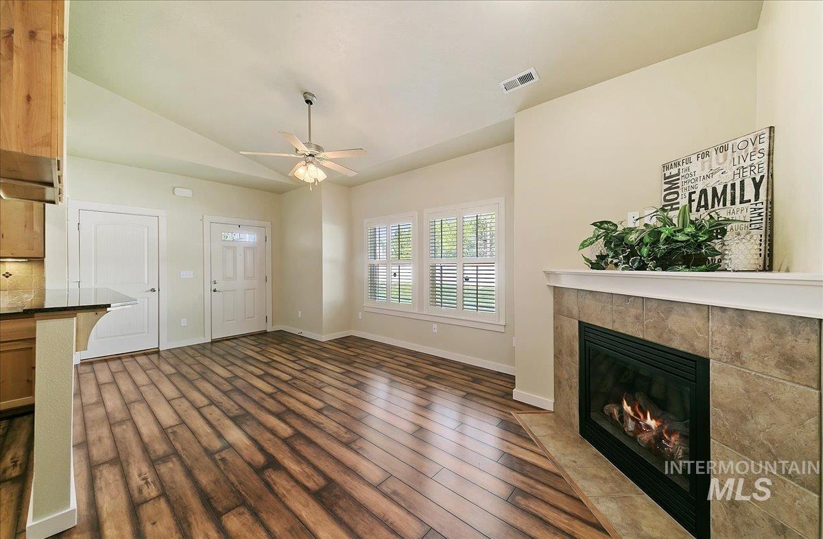 Sunny Great Room with a tile fireplace, wood-look Laminate floors, a ceiling fan, and vaulted ceiling!