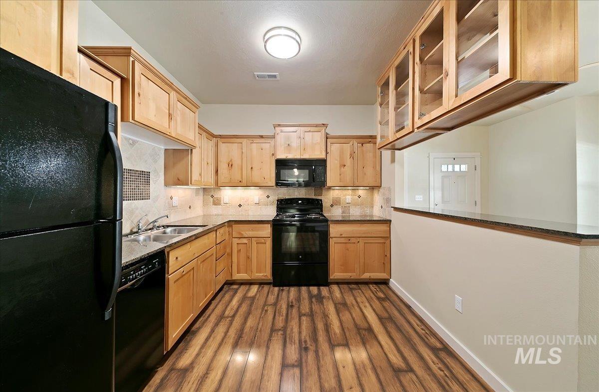 Kitchen with custom knotty maple cabinetry has ample storage options along with Decorative Glass hanging cabinet to Display your favorite Dishes & Pottery!