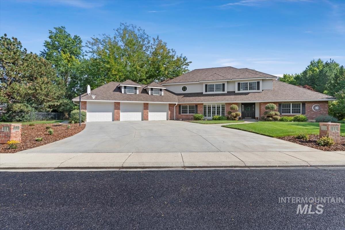 Traditional-style house featuring driveway, brick siding, a front lawn, and an attached garage