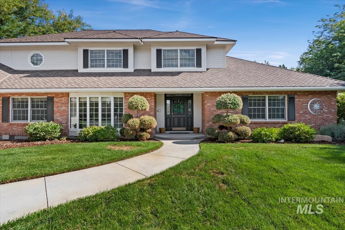 Traditional-style home with brick siding, a front yard, and roof with shingles