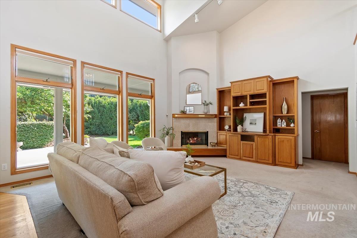 Living room with a high ceiling, a tile fireplace, and light carpet