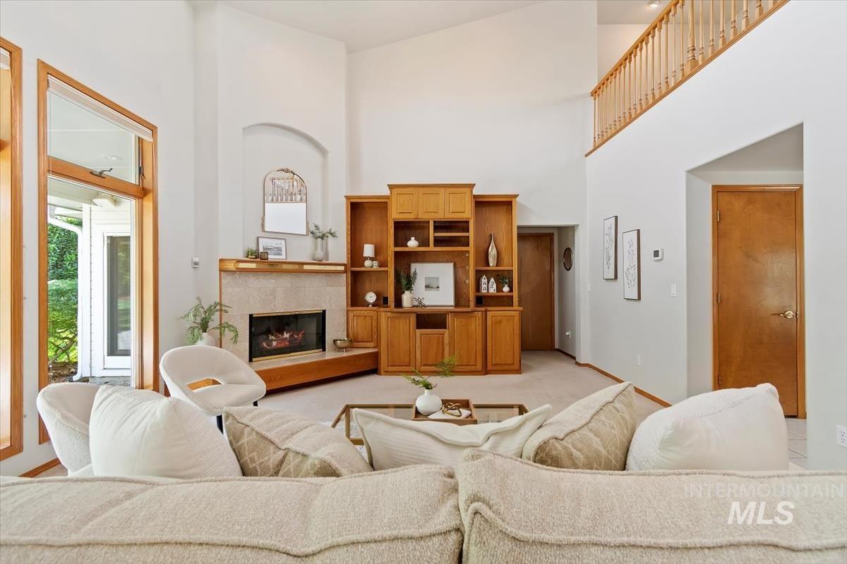 Living area featuring a high ceiling, a fireplace, and light carpet