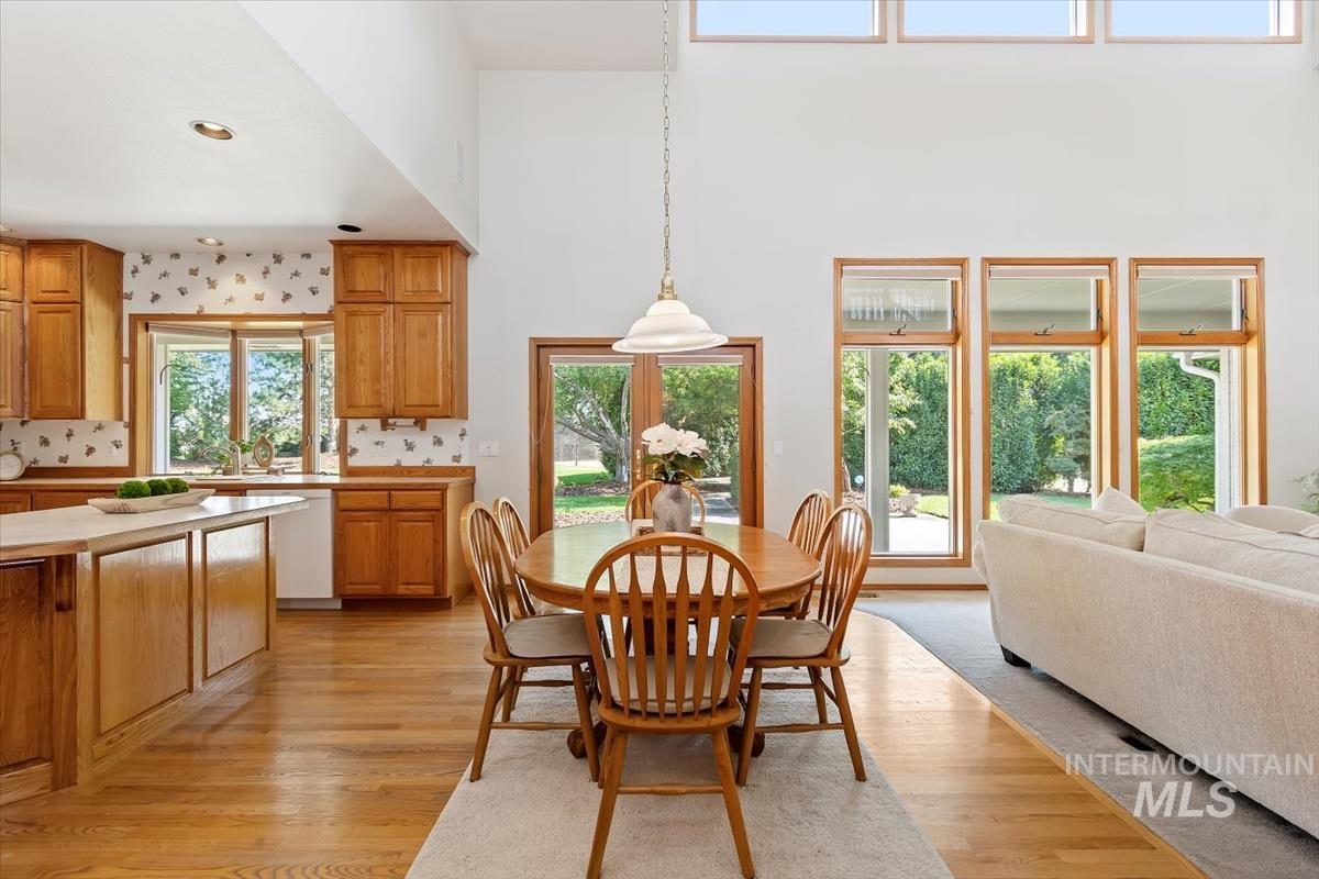 Dining room with light wood finished floors, recessed lighting, and a high ceiling