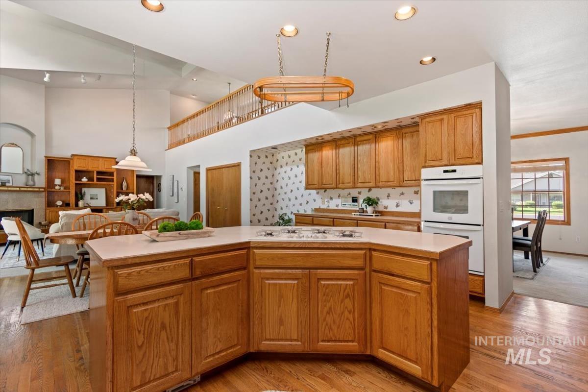 Kitchen with light countertops, open floor plan, brown cabinets, light wood finished floors, and a kitchen island