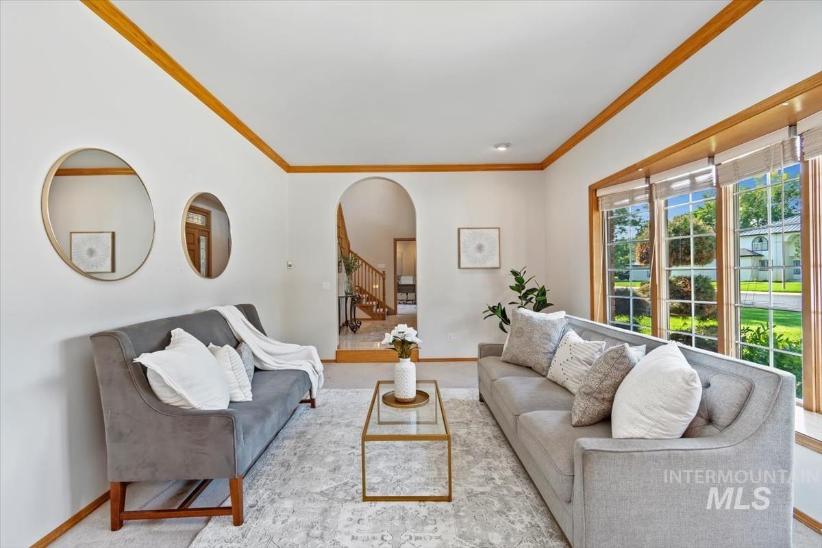Living room featuring crown molding, arched walkways, and stairs