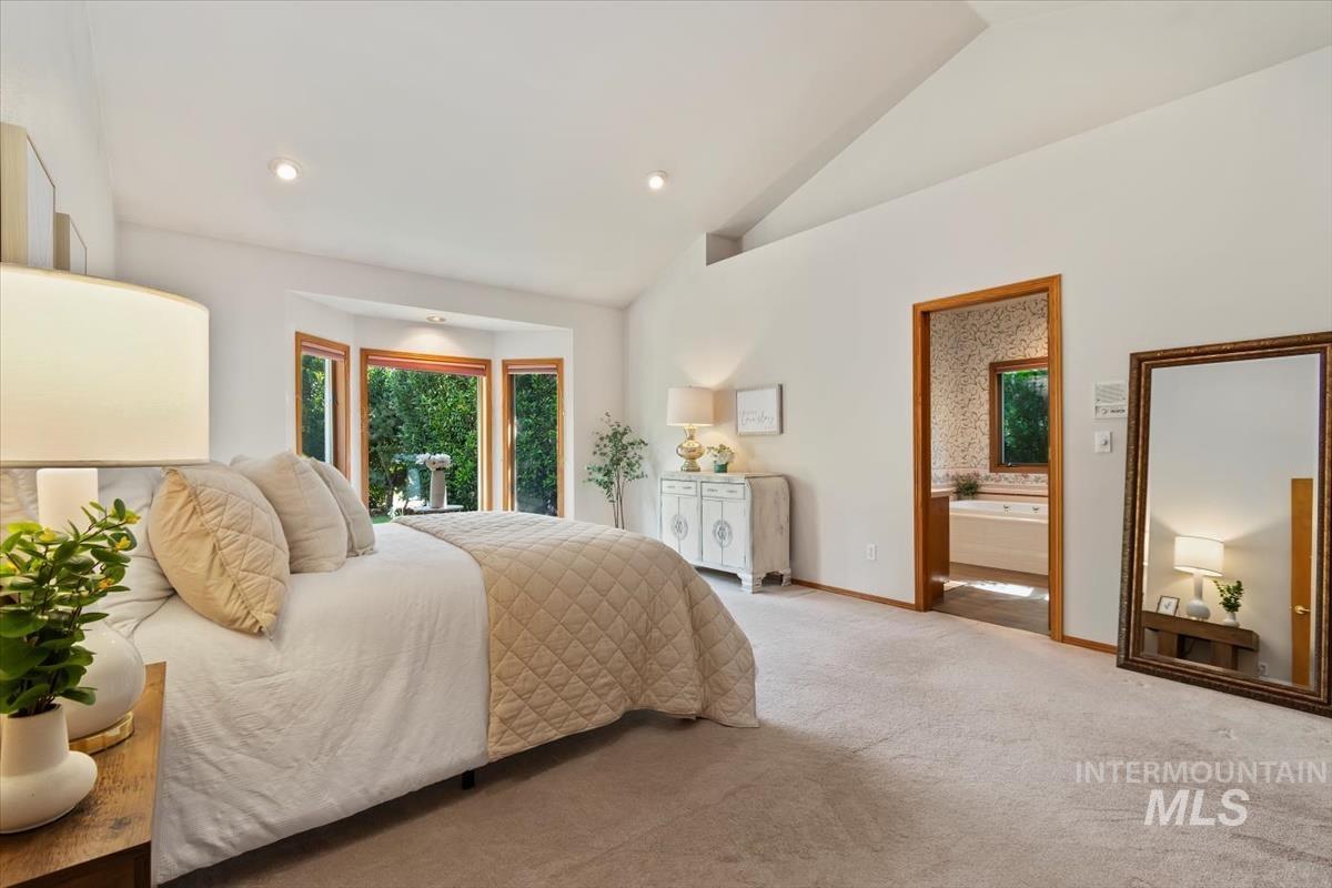 Bedroom featuring multiple windows, carpet flooring, recessed lighting, ensuite bathroom, and high vaulted ceiling