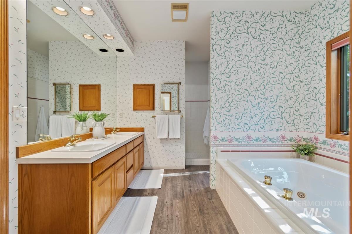 Full bath featuring dark wood-style floors, double vanity, a whirlpool tub, and recessed lighting