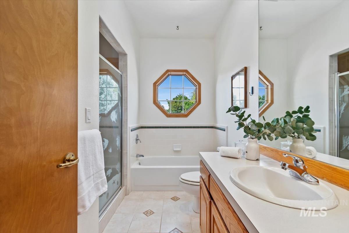 Bathroom with vanity, a shower stall, a garden tub, and light tile patterned flooring