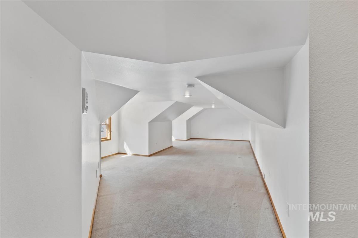 Bonus room featuring light colored carpet and baseboards