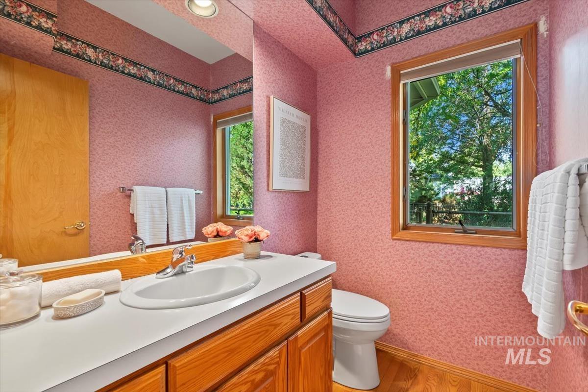 Bathroom featuring light wood finished floors, vanity, and wallpapered walls