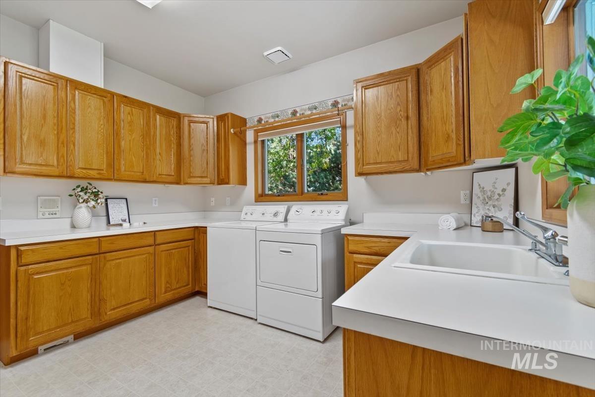Laundry area featuring independent washer and dryer, cabinet space, and light floors