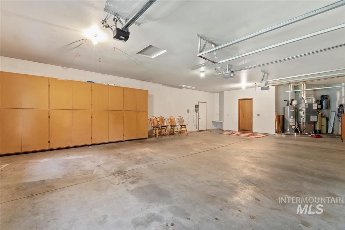 Garage with water heater, heating unit, and a garage door opener