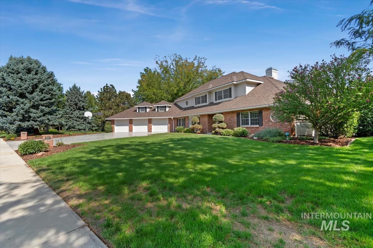 Traditional-style house with a garage, a chimney, brick siding, and a front yard