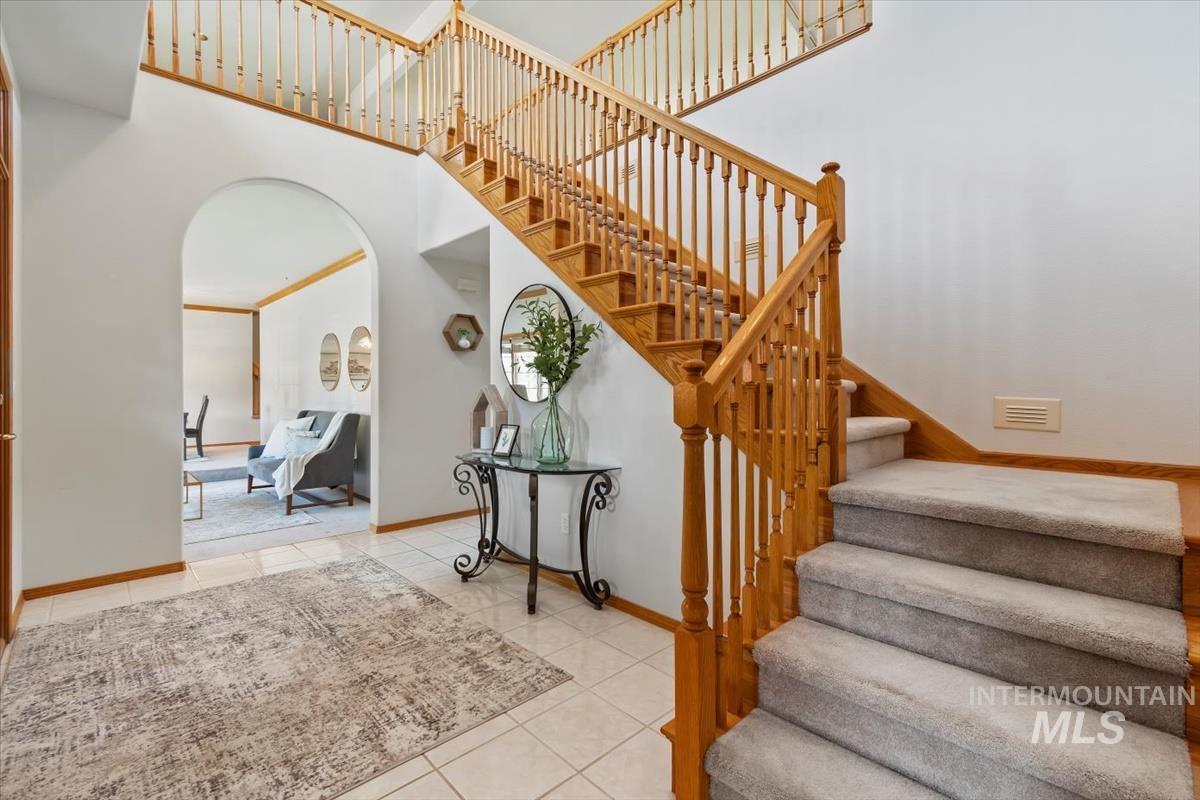 Stairs featuring a towering ceiling, arched walkways, tile patterned flooring, and ornamental molding