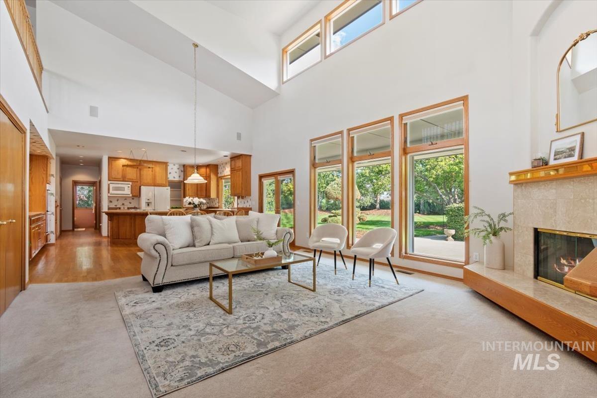 Living area featuring a high ceiling, a fireplace, and light carpet