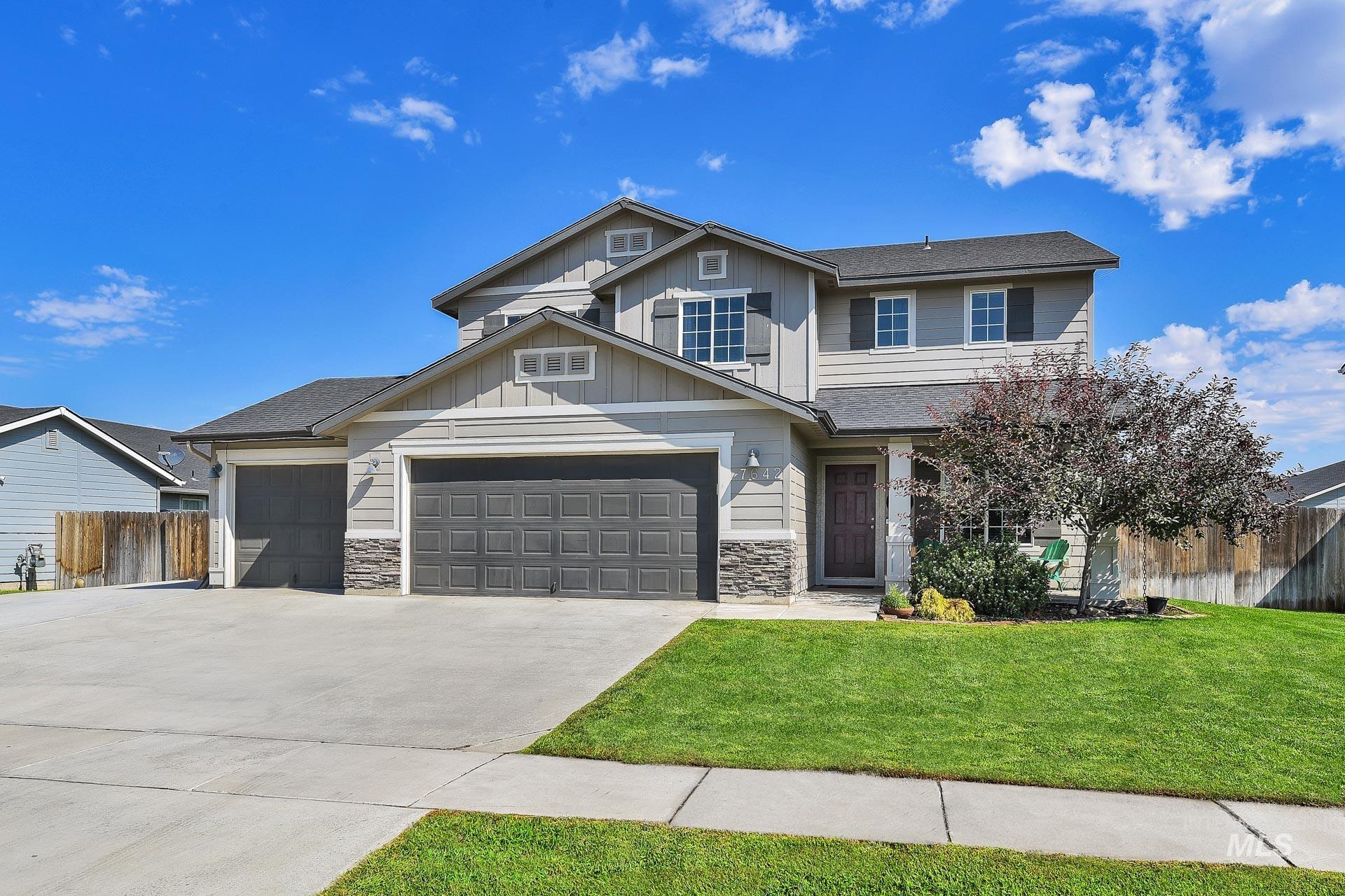 Craftsman inspired home featuring stone siding, concrete driveway, board and batten siding, and an attached garage