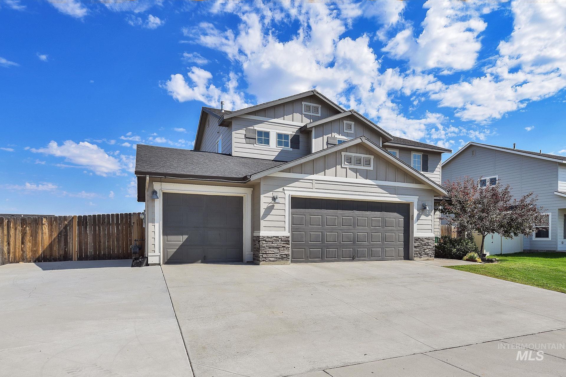 Craftsman-style home featuring board and batten siding, driveway, stone siding, and an attached garage