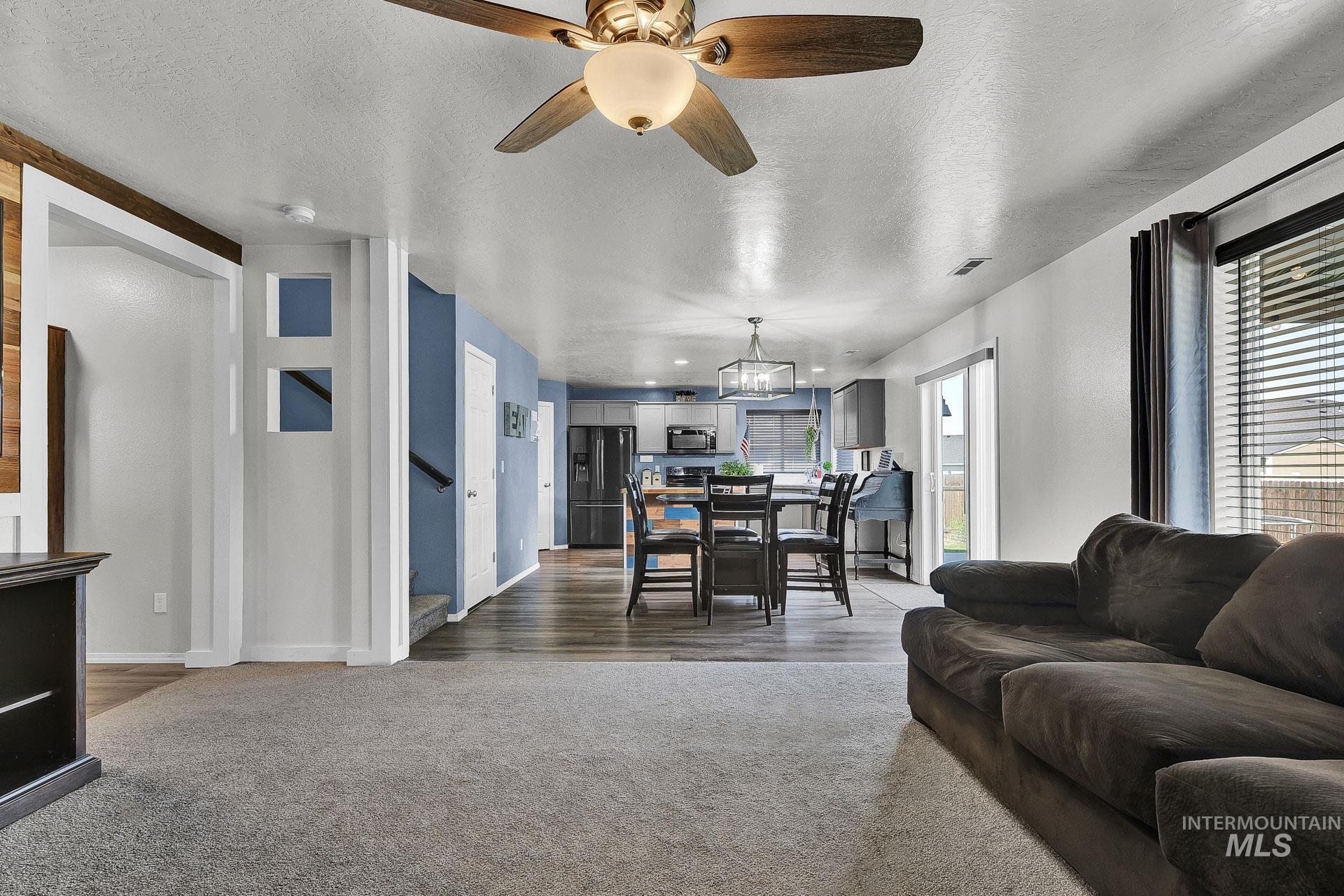 Living area featuring a textured ceiling, ceiling fan, and carpet