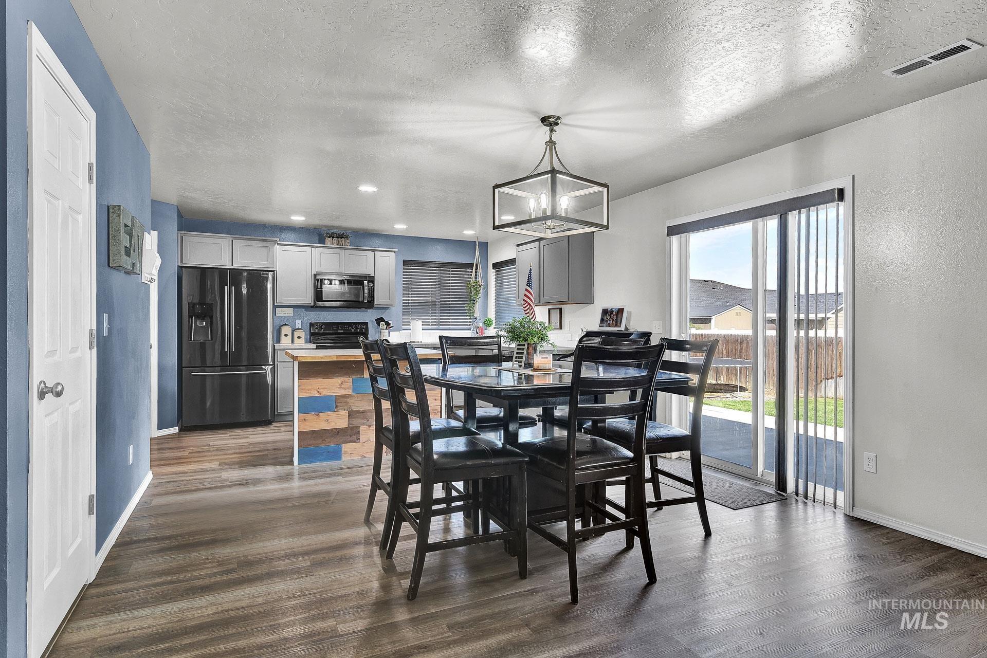 Dining room with a textured ceiling, dark wood finished floors, recessed lighting, and a chandelier