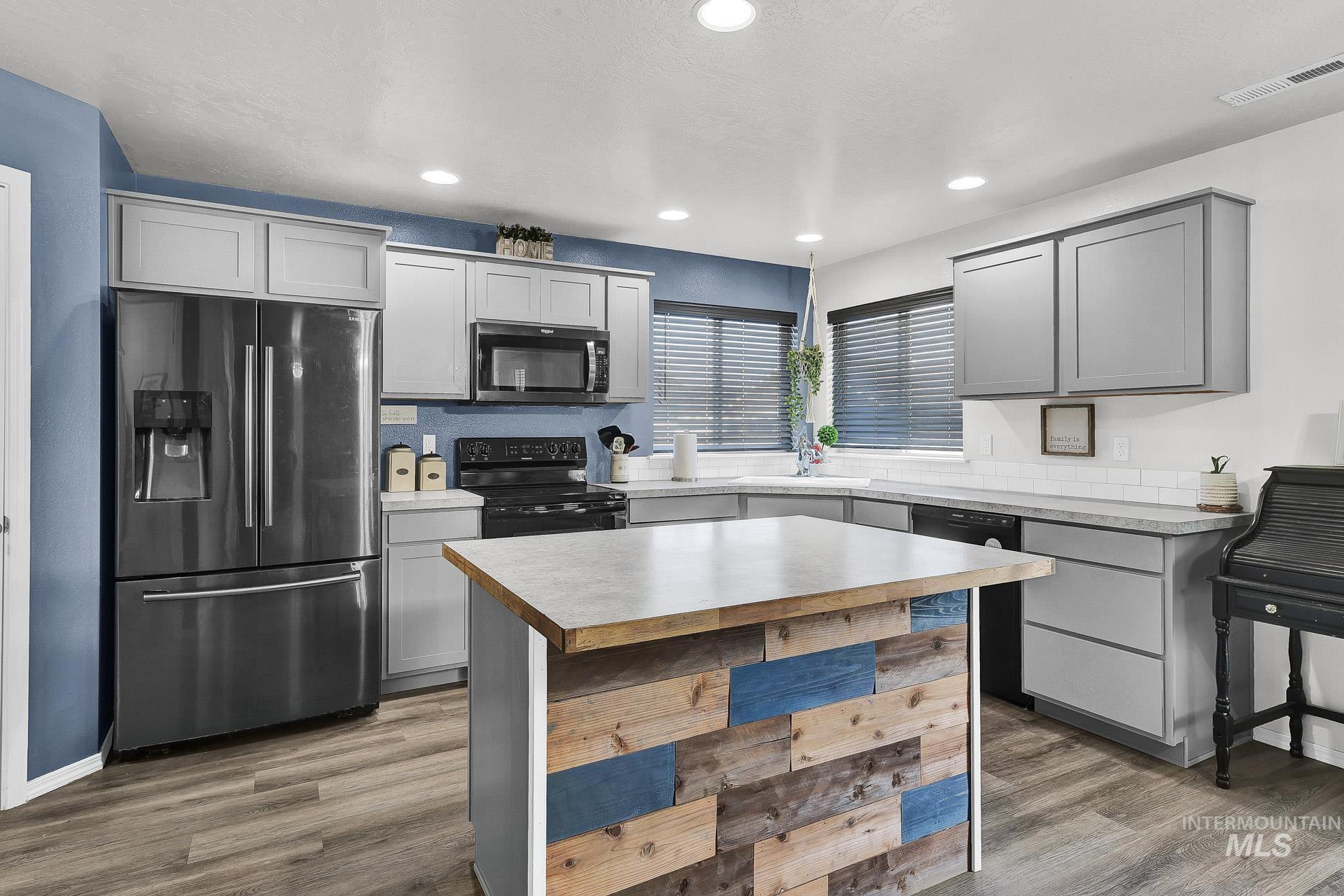 Kitchen featuring black appliances, gray cabinetry, a center island, light wood finished floors, and recessed lighting