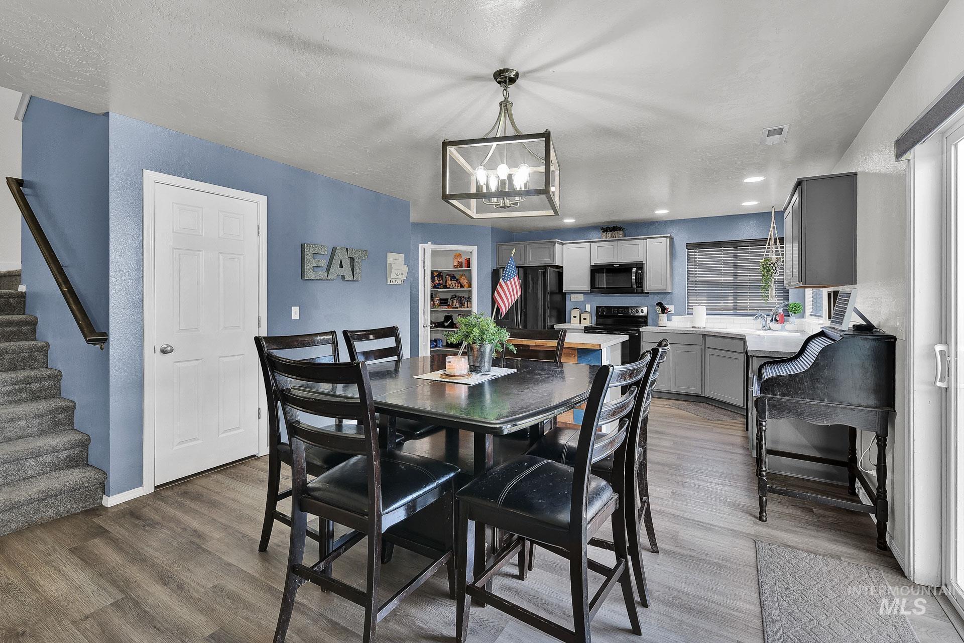 Dining room featuring stairs, wood finished floors, recessed lighting, a textured ceiling, and a chandelier