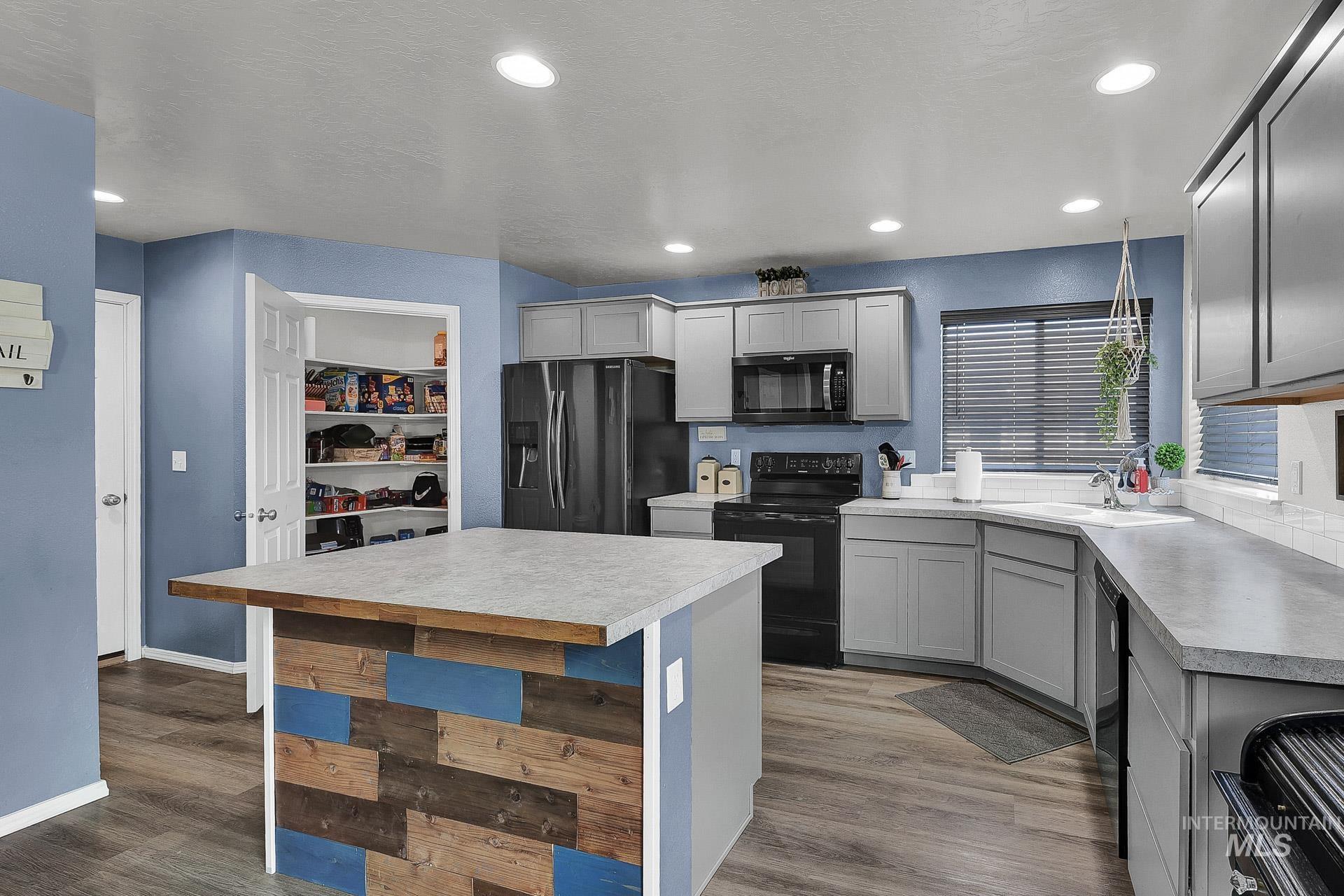 Kitchen featuring black appliances, light countertops, gray cabinets, light wood-type flooring, and recessed lighting