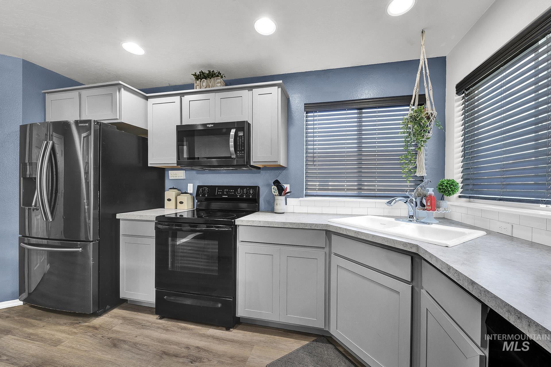 Kitchen with black appliances, gray cabinetry, light wood-style flooring, light countertops, and recessed lighting
