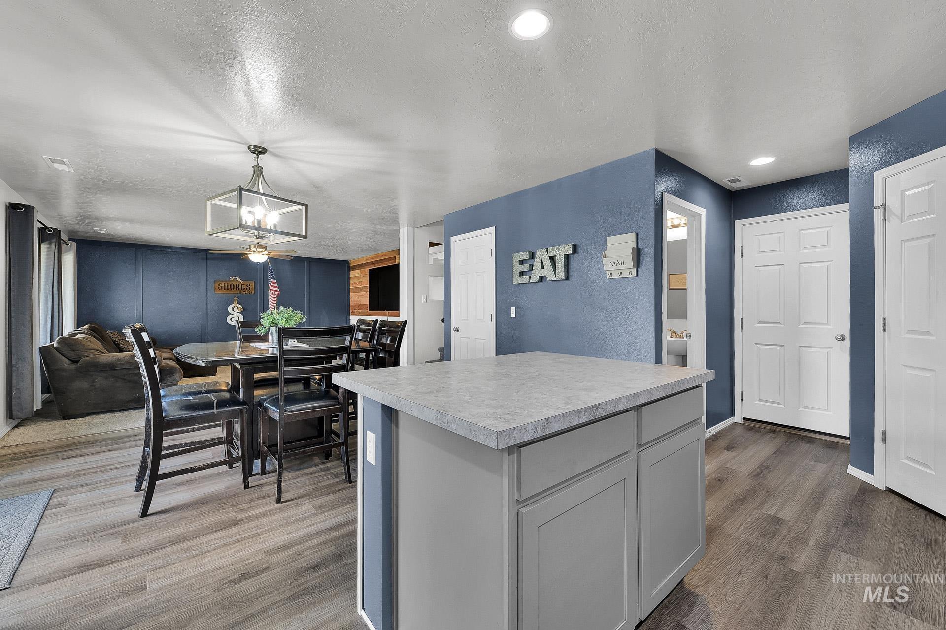 Kitchen with a center island, light countertops, light wood-style flooring, gray cabinetry, and a textured ceiling