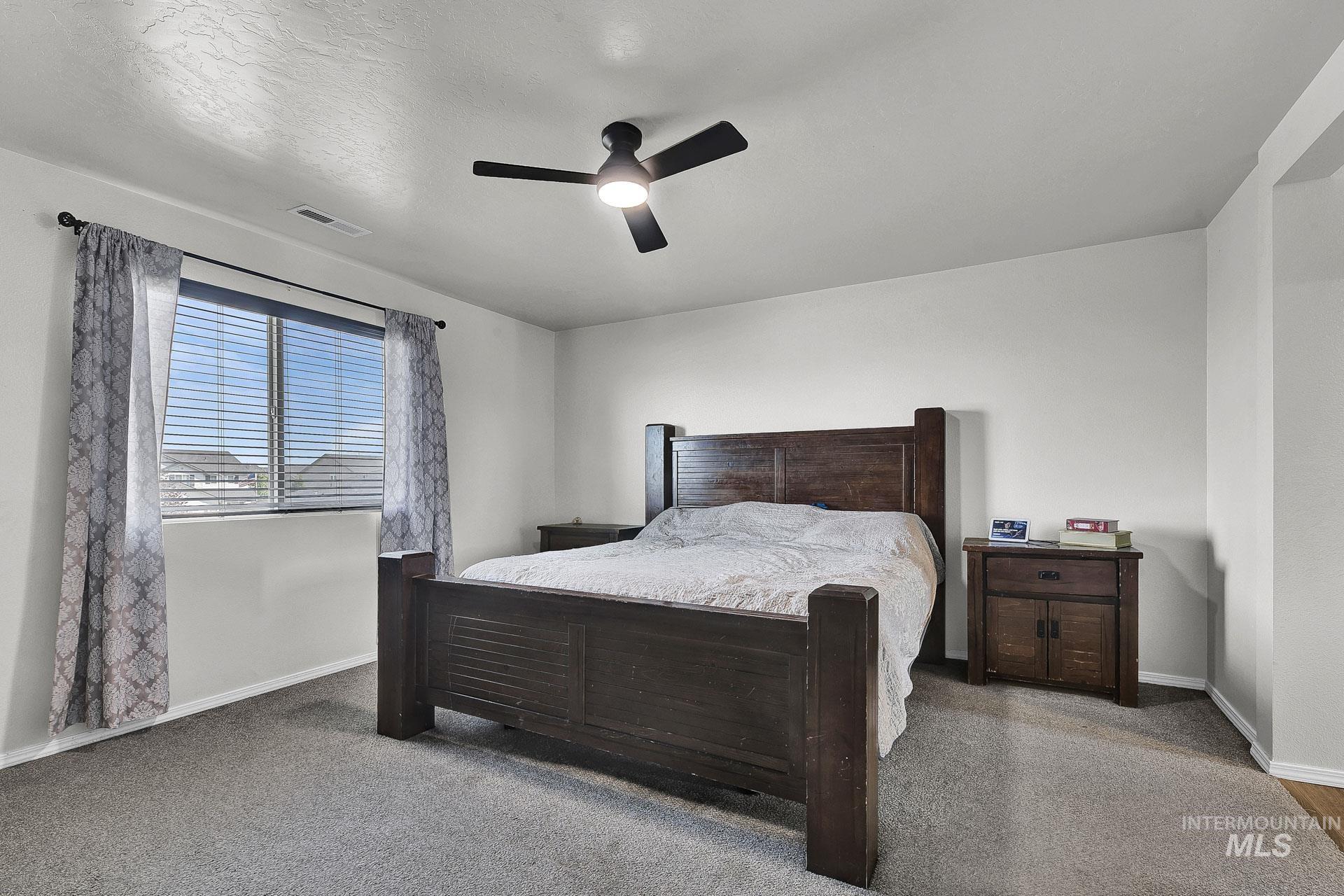 Bedroom featuring carpet flooring, a ceiling fan, and a textured ceiling