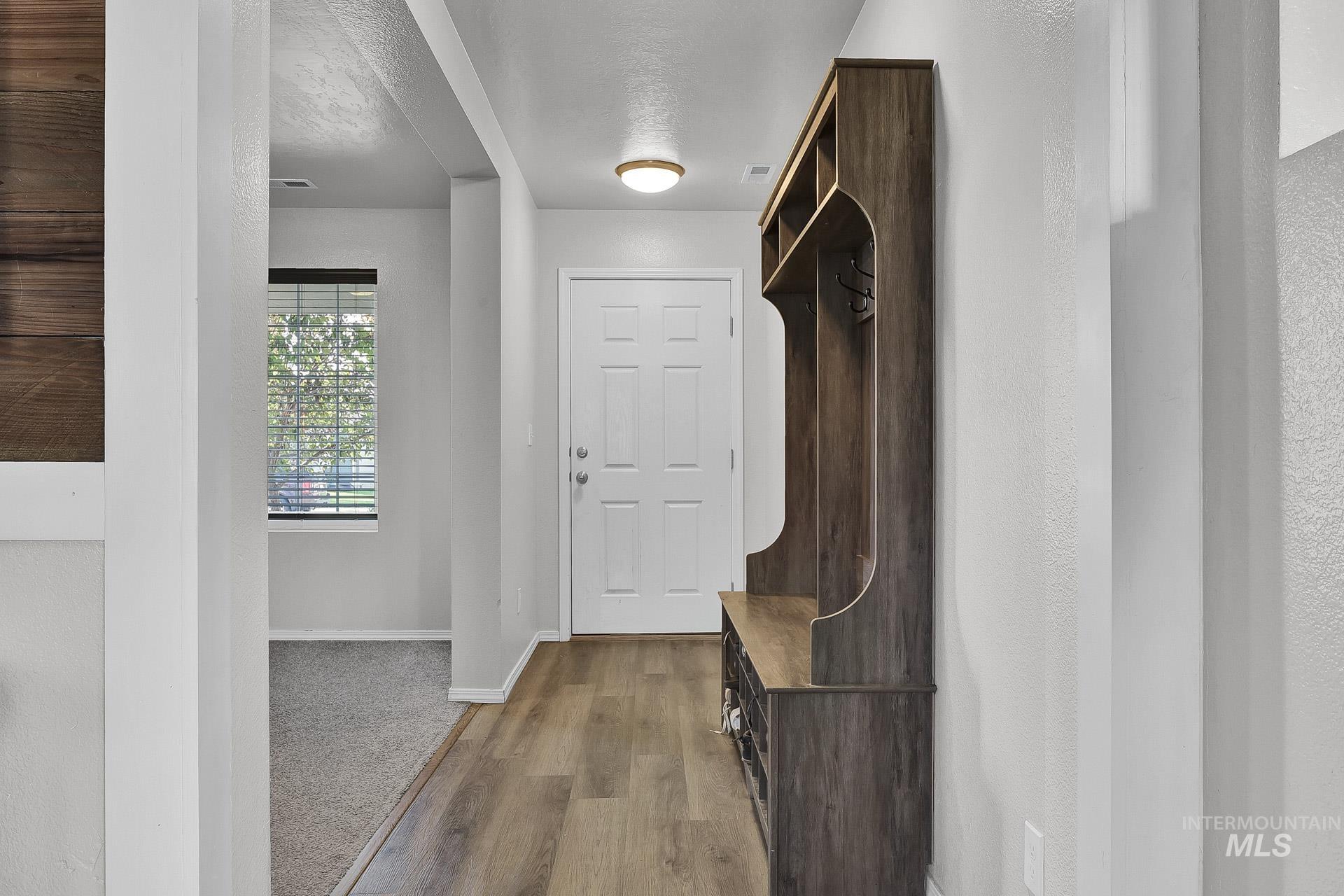 Mudroom with light wood finished floors and a textured ceiling
