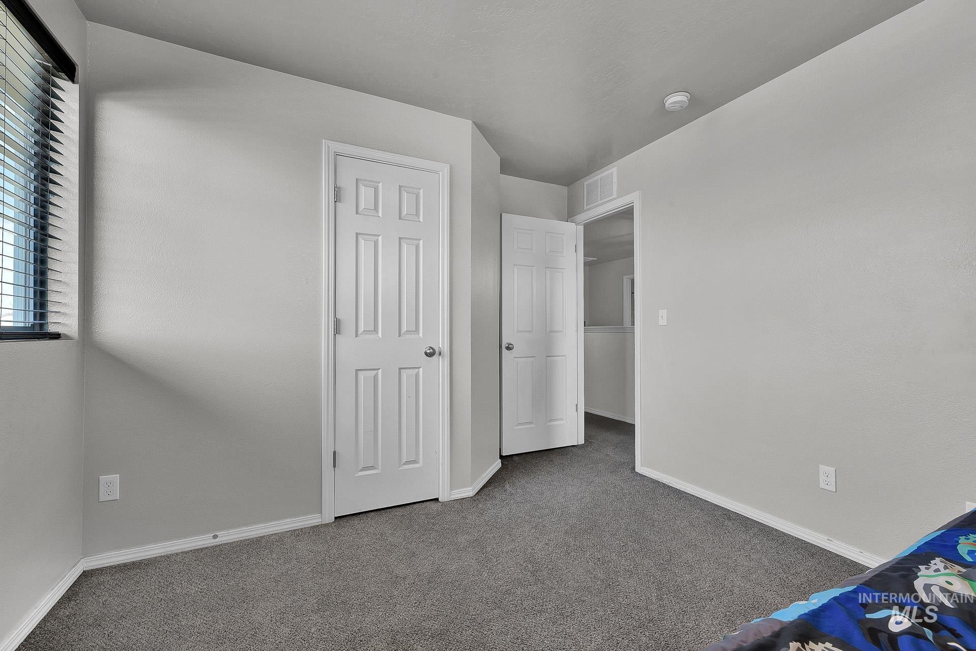 Unfurnished bedroom with carpet flooring and baseboards