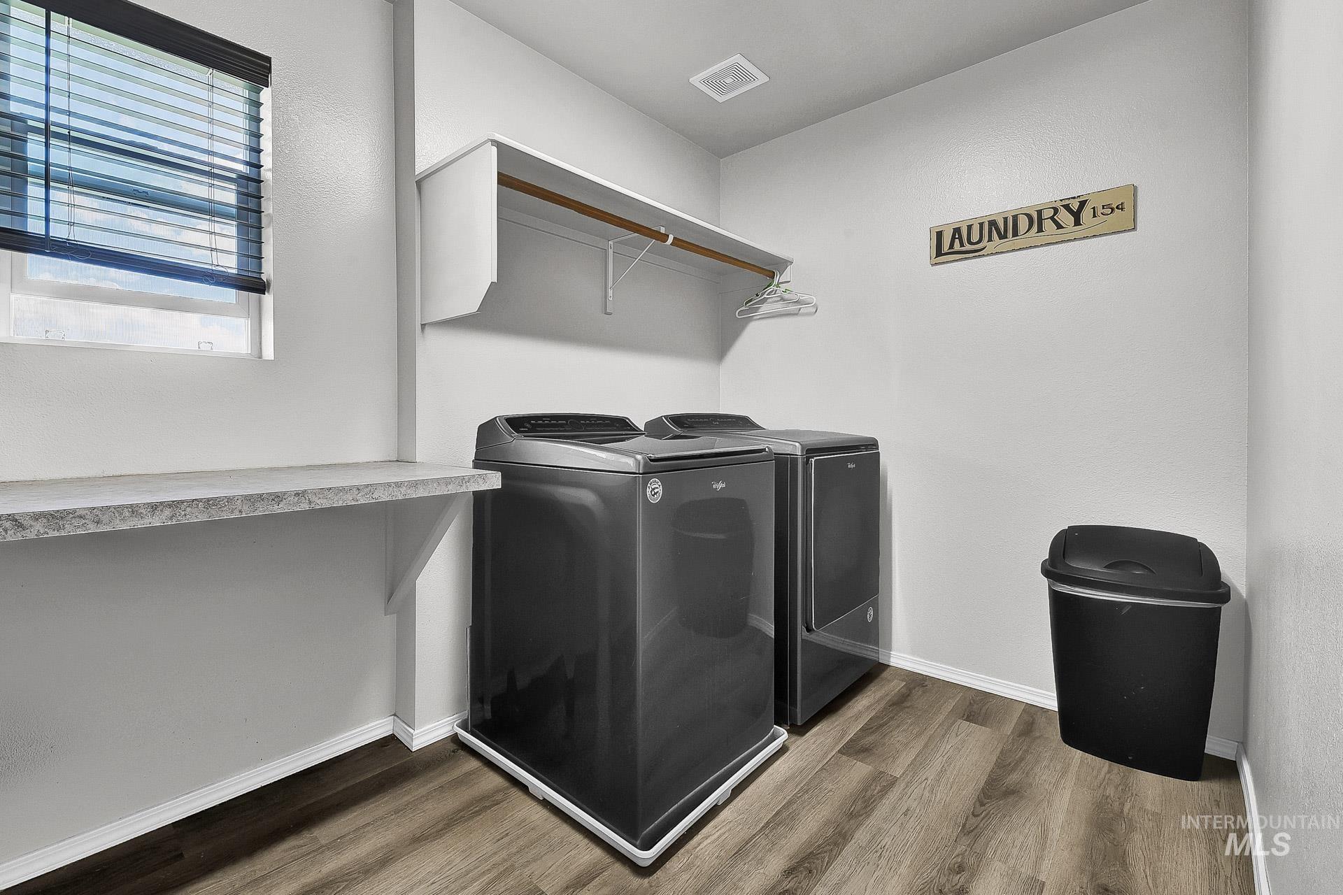 Laundry room with dark wood finished floors and washing machine and dryer