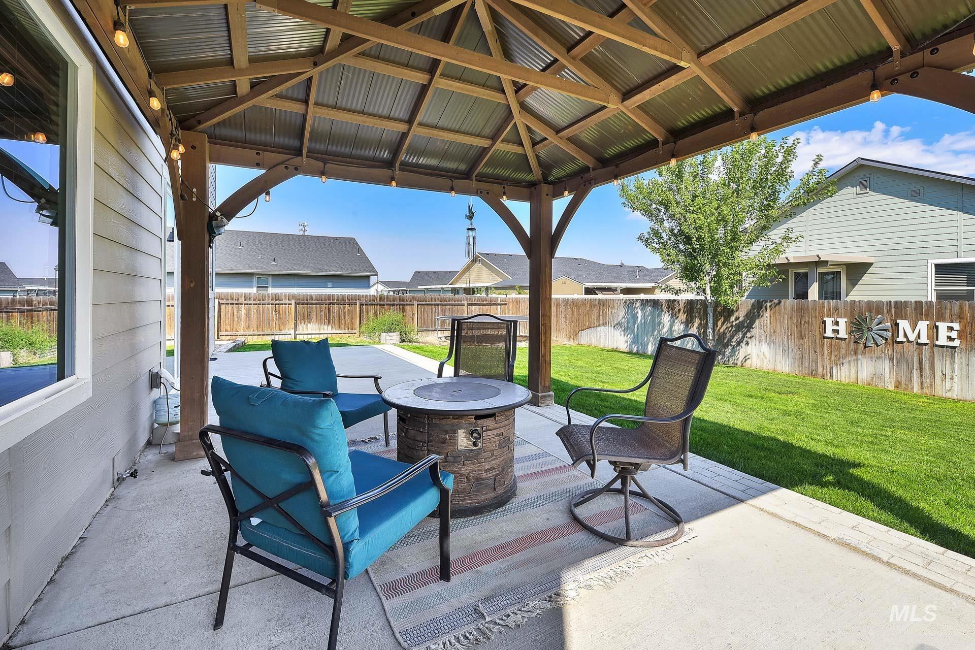Fenced backyard featuring an outdoor fire pit, a patio area, and a gazebo