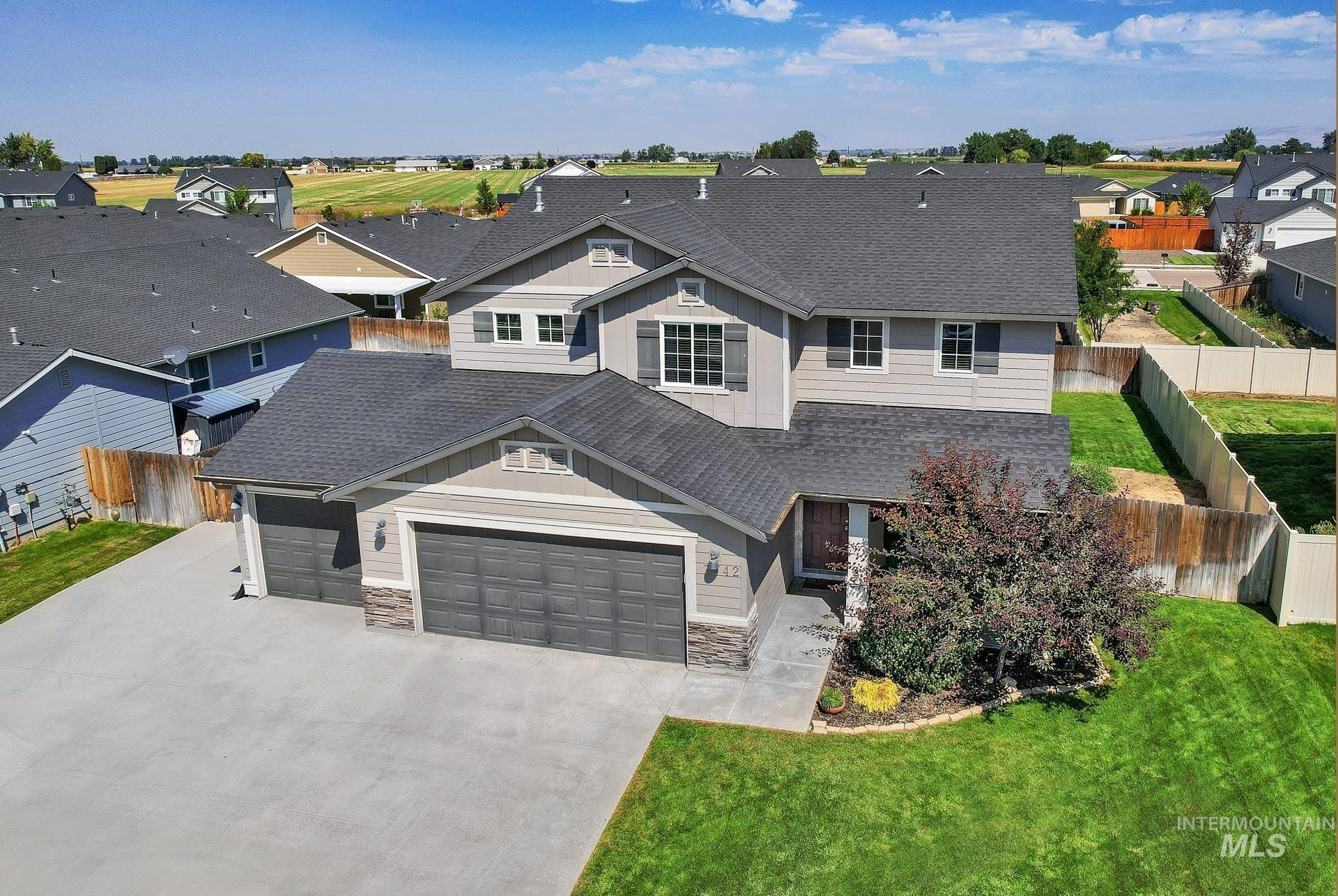 View of front of property featuring roof with shingles, stone siding, a garage, concrete driveway, and a residential view