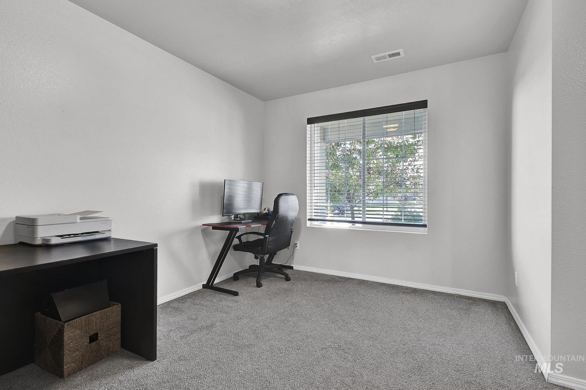 Home office with light colored carpet and baseboards
