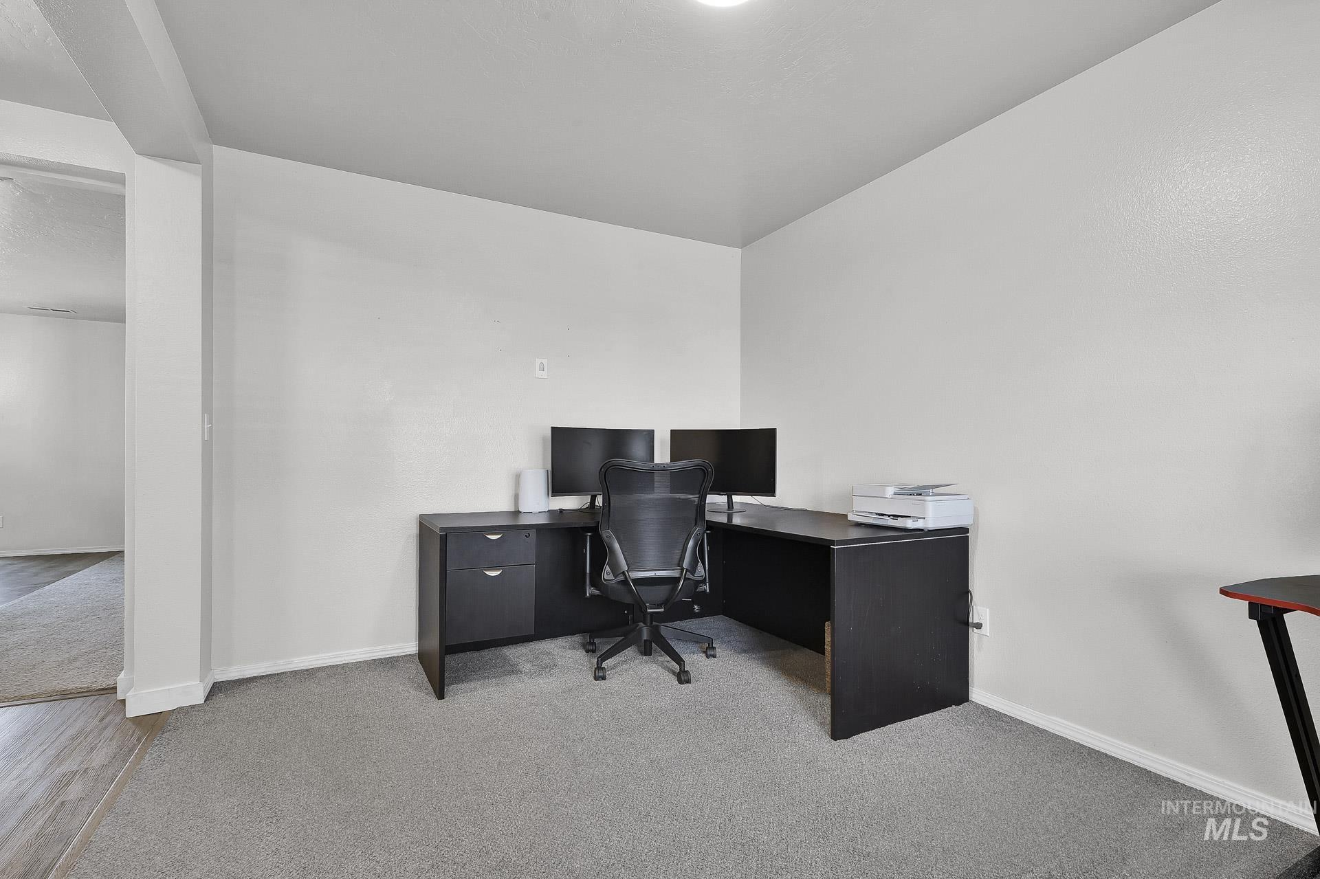 Home office with baseboards and light colored carpet
