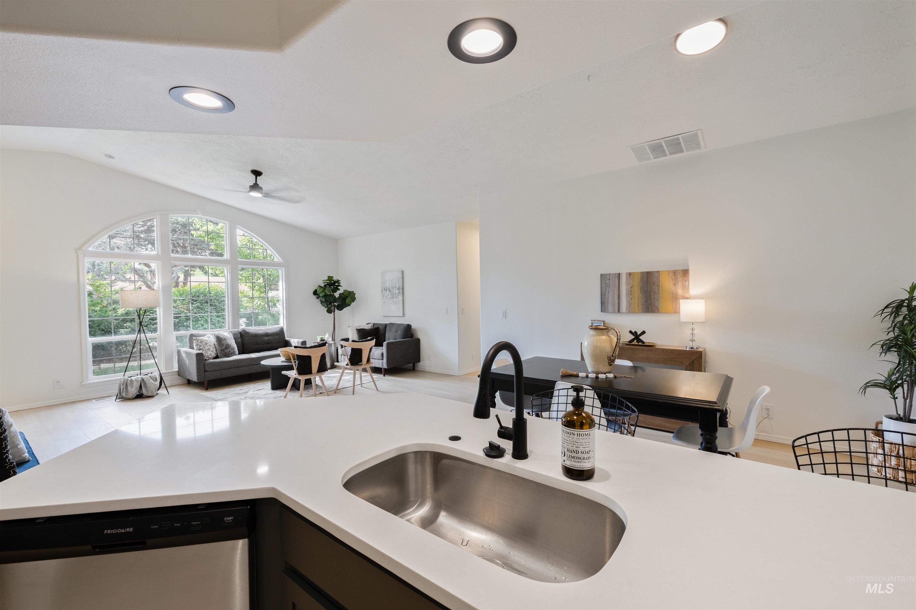 Kitchen featuring open floor plan, dishwasher, recessed lighting, vaulted ceiling, and light stone countertops