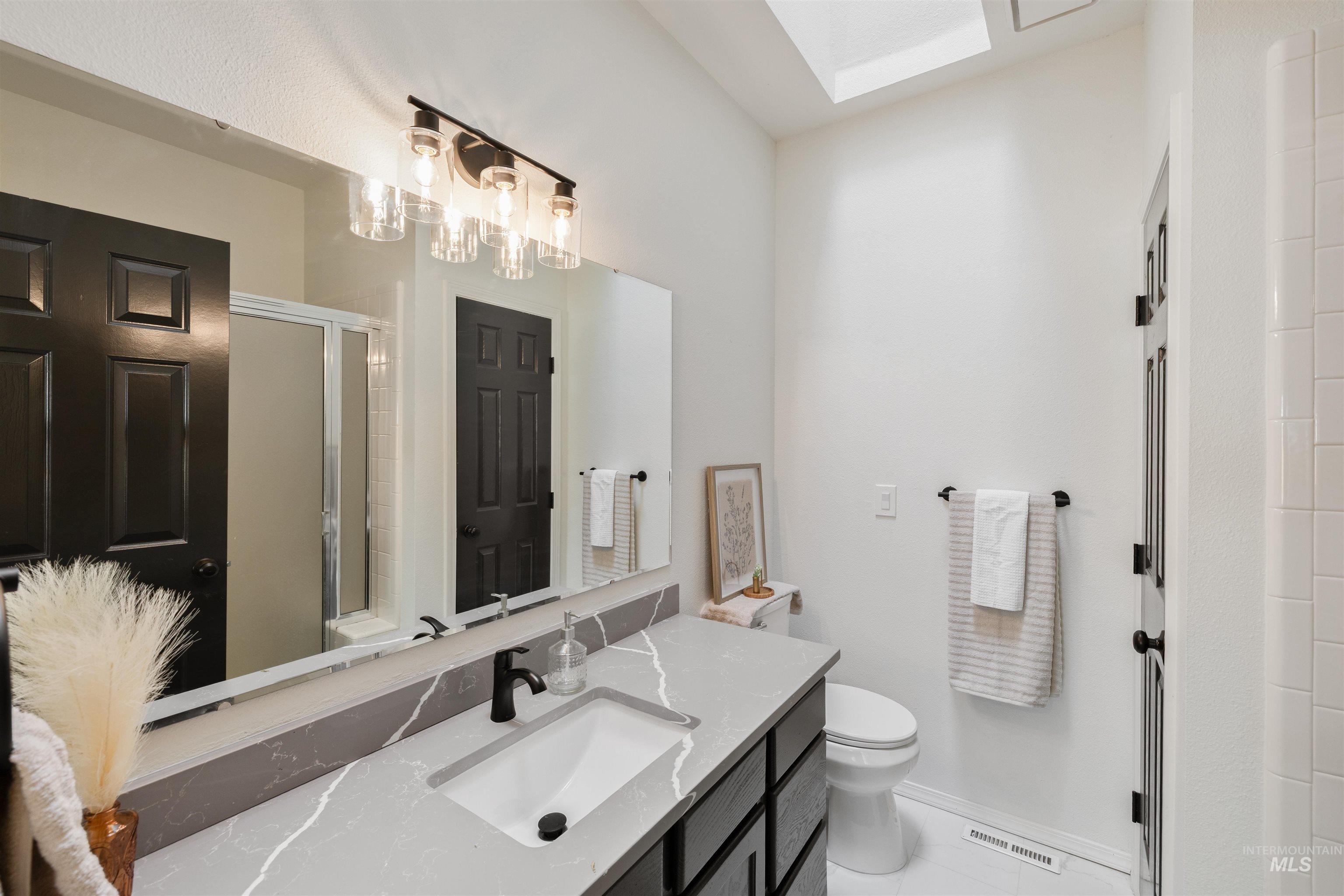 Full bath featuring vanity, a stall shower, and a skylight