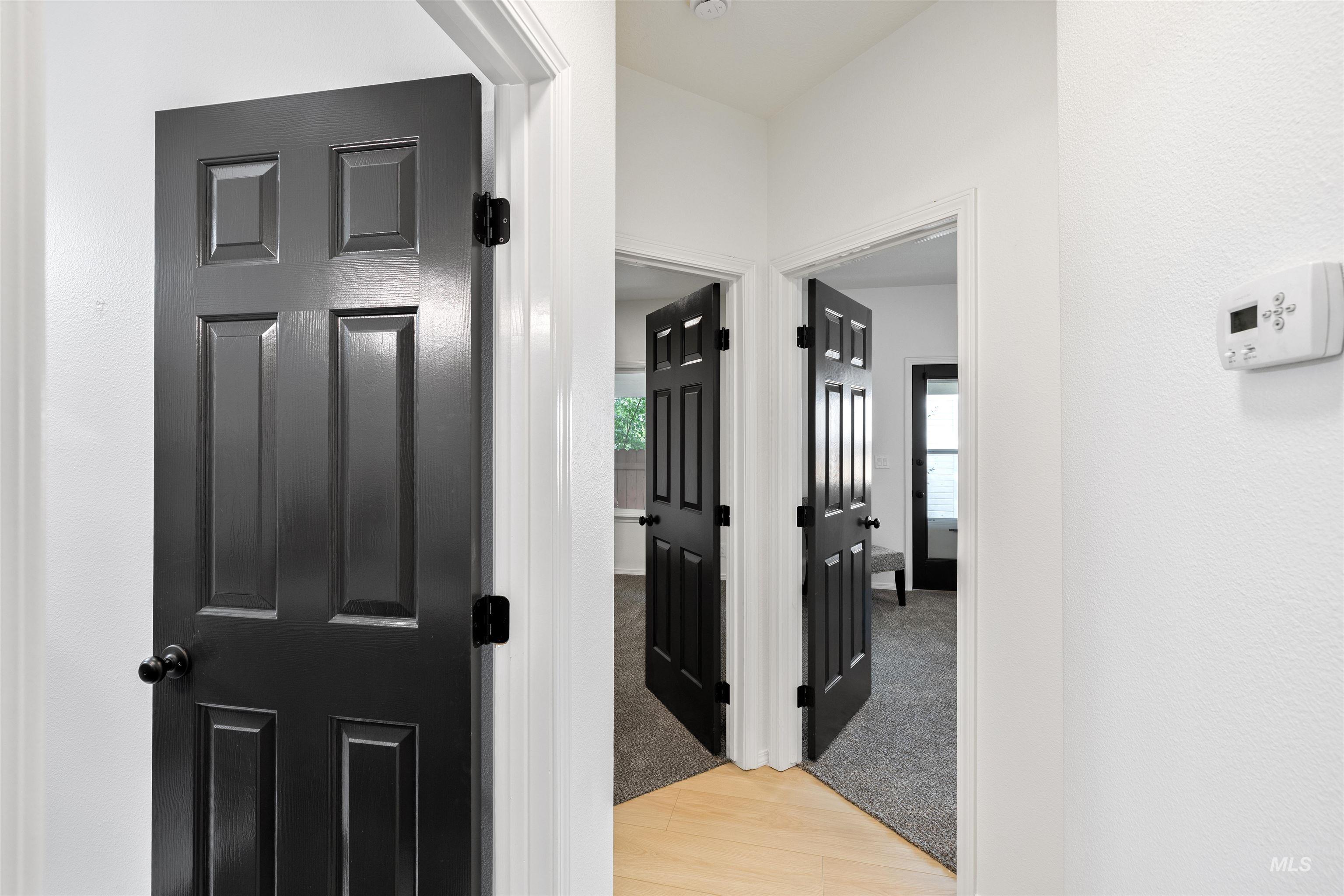 Corridor with light wood-style flooring and light colored carpet