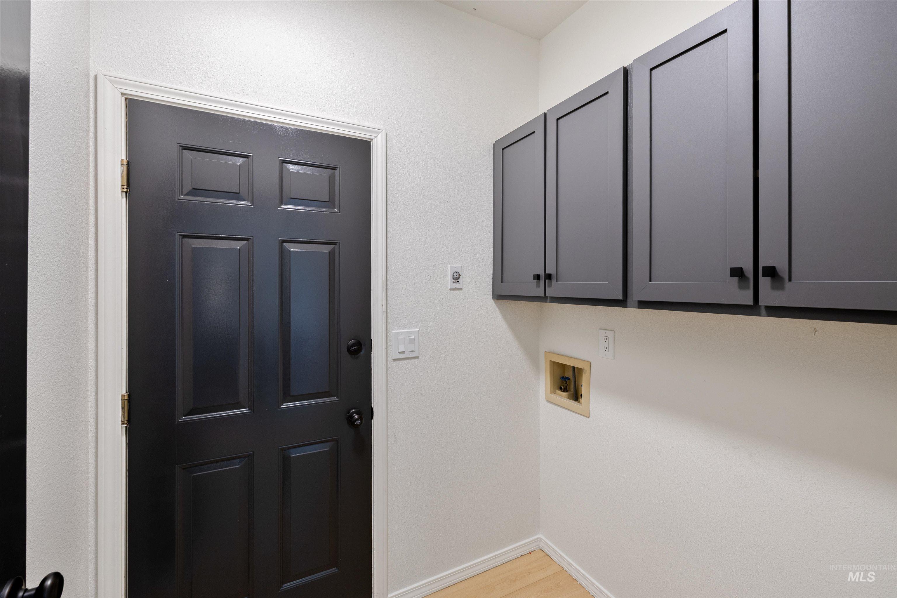 Laundry area featuring cabinet space, hookup for a washing machine, and light wood-style flooring
