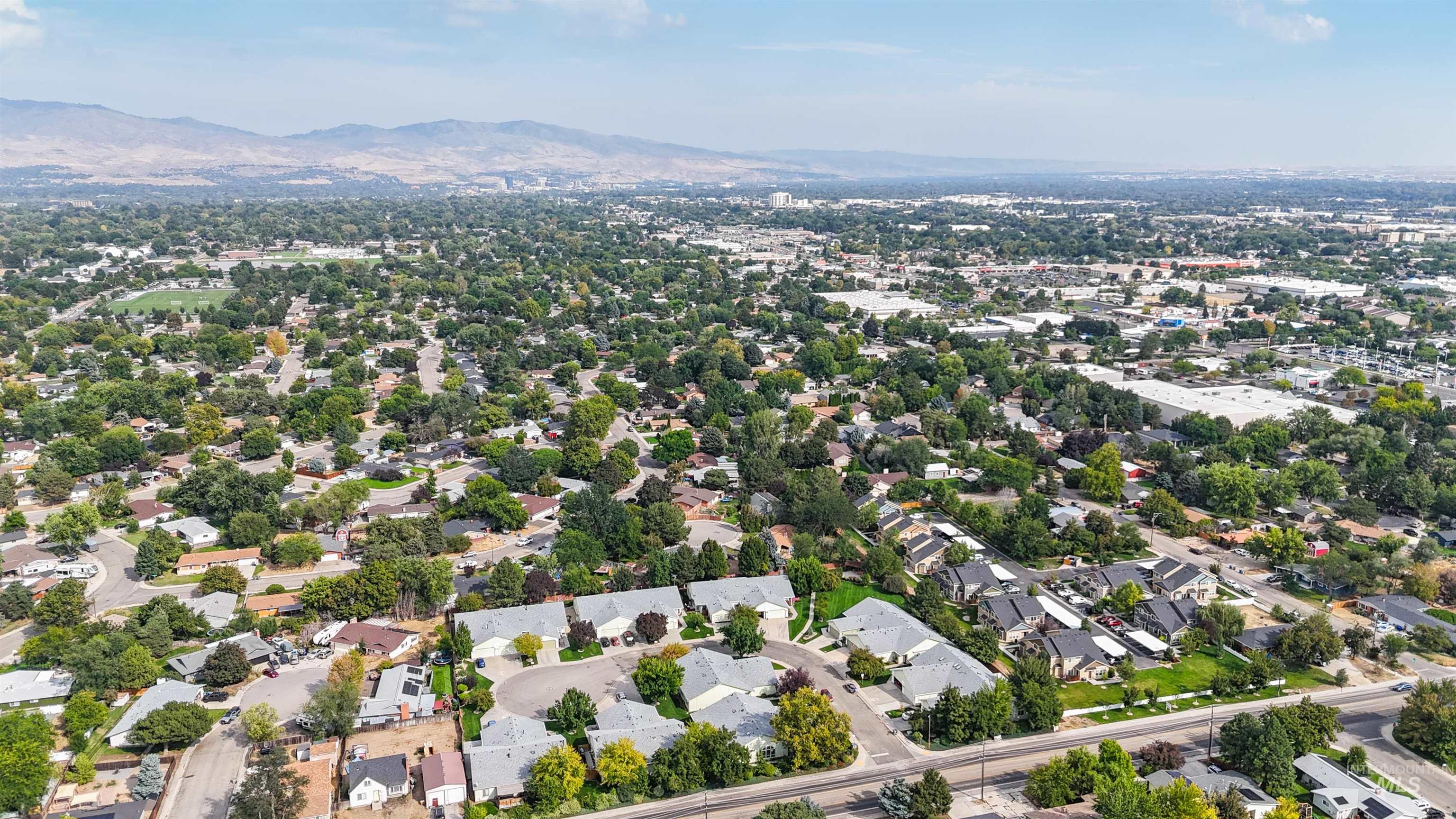 Aerial view of property and surrounding area featuring a mountain backdrop and nearby suburban area