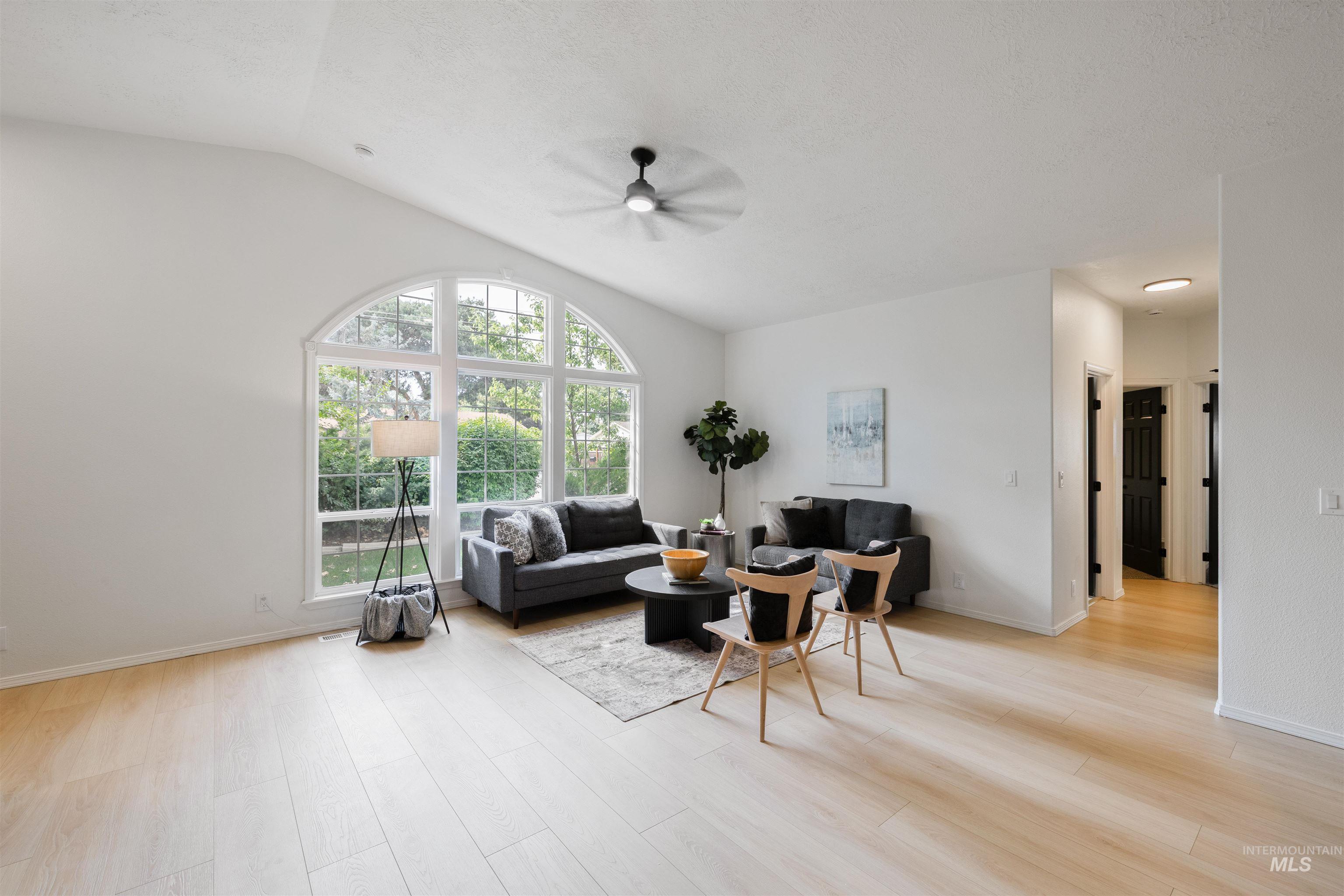 Living area with light wood-style flooring, lofted ceiling, and ceiling fan